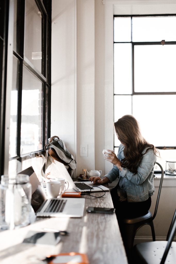 a woman drinking coffee and writing in a cafe